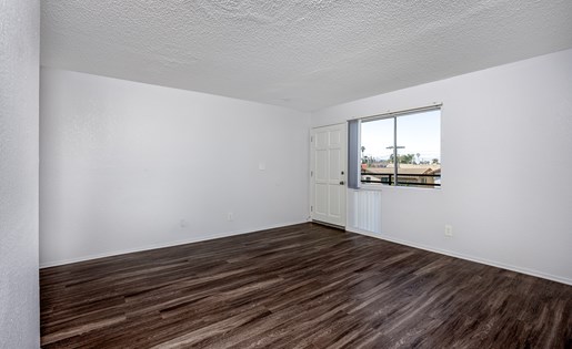Empty room with wooden flooring and a window.